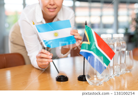 Unrecognizable girl set midget flags of South Africa and Argentina before international negotiations Unrecognizable girl set midget flags of South Africa and Argentina before international negotiations 138100254