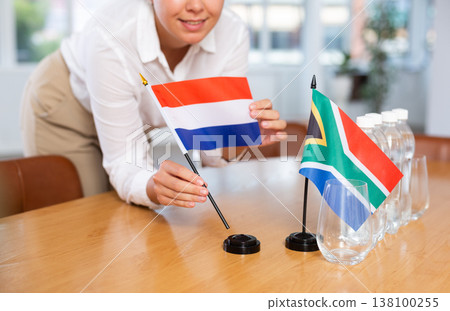 Little flag of South Africa on table and flag of Netherlands put next to it by young woman Little flag of South Africa on table and flag of Netherlands put next to it by young woman 138100255