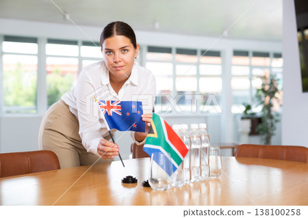 Positive young woman putting little flag of Australia on table next to the flag of South Africa Positive young woman putting little flag of Australia on table next to the flag of South Africa 138100258