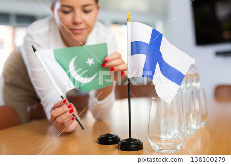 Woman secretary prepares an office for negotiations - she places flags of Finland and Pakistan table Woman secretary prepares an office for negotiations - she places flags of Finland and Pakistan table 138100279