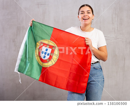 Happy girl stands with flag of Portugal. Isolated on gray background Happy girl stands with flag of Portugal. Isolated on gray background 138100300