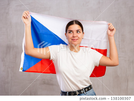 Calm cheerleader girl holds Czechia flag in her hands. Isolated on gray background Calm cheerleader girl holds Czechia flag in her hands. Isolated on gray background 138100307