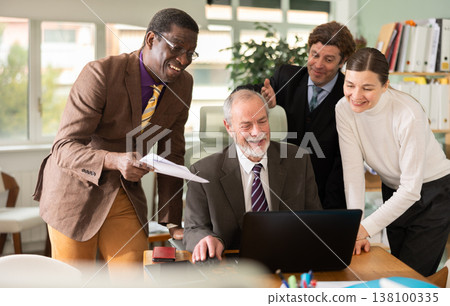 Group of office employees look at the notebook together and rejoice 138100335