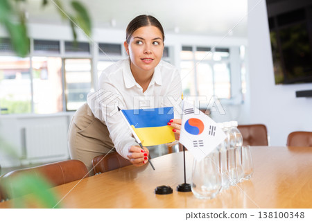 Businesswoman placing flags of Ukraine and South Korea on negotiating table 138100348