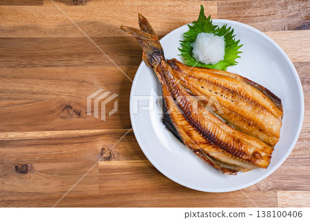 Grilled Atka mackerel with salt, served with grated daikon radish (Japanese style grilled fish), served on a wooden table. Grilled Atka mackerel with salt, served with grated daikon radish (Japanese style grilled fish), served on a wooden table. 138100406
