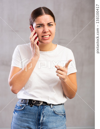 Angry young woman talking on mobile phone 138100417