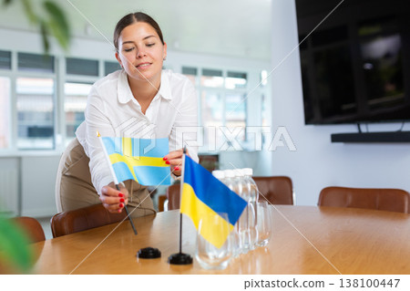 Businesswoman setting flags of Ukraine and Sweden on negotiating table 138100447