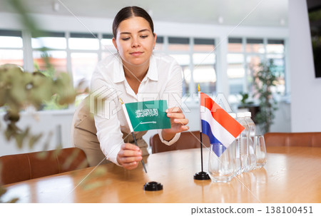 Young lady sets miniatures flags of Netherlands and Saudi Arabia for international negotiations Young lady sets miniatures flags of Netherlands and Saudi Arabia for international negotiations 138100451