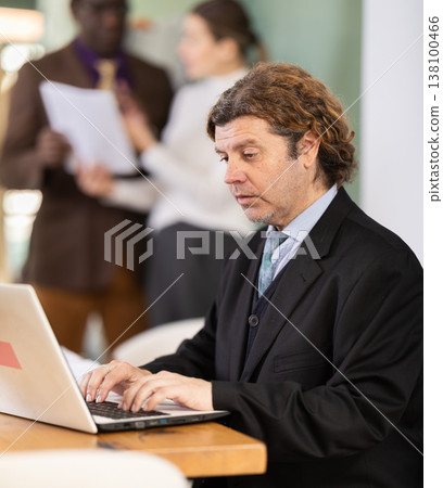 Man sitting at desk is working on laptop computer. Working day in office Man sitting at desk is working on laptop computer. Working day in office 138100466