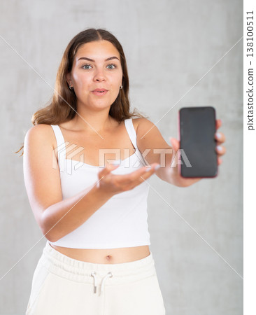 Smiling girl showing modern smartphone with blank screen 138100511