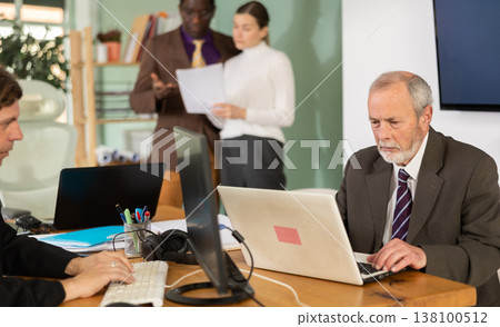 Elderly man working in office with laptop 138100512