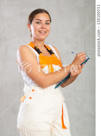 Happy emotional woman in overalls making entries in invoice or warrant Happy emotional woman in overalls making entries in invoice or warrant 138100551