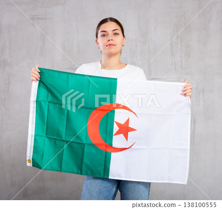 Focused woman holding Algeria flag Focused woman holding Algeria flag 138100555