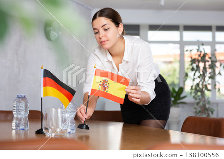 Young female attendant putting up flags for international negotiations between germany and spain Young female attendant putting up flags for international negotiations between germany and spain 138100556