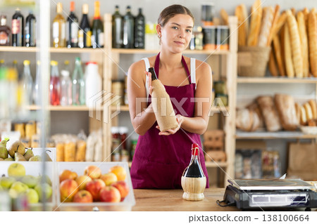 Young female seller offering wine in grocery store Young female seller offering wine in grocery store 138100664