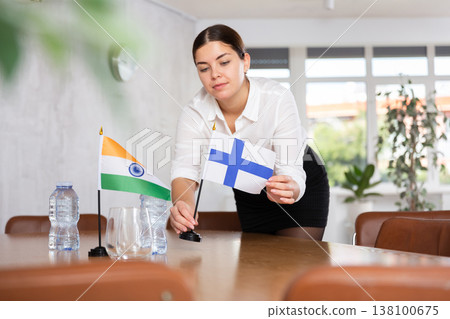 Young female attendant putting up flags for international negotiations between india and finland Young female attendant putting up flags for international negotiations between india and finland 138100675