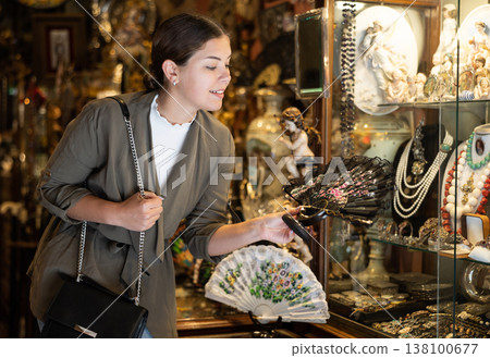 Positive woman tourist chooses hand fan in crafts shop 138100677