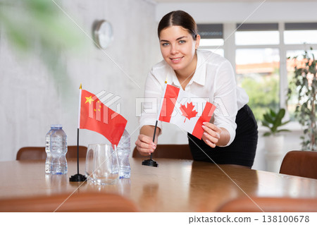 Young female attendant putting up flags for international negotiations between china and canada Young female attendant putting up flags for international negotiations between china and canada 138100678
