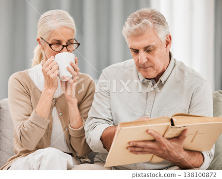 Worship, bible and senior couple with a book in a living room relax, reading and bond with coffee at home. God, faith and retired elderly people with scripture, study or gospel, love and Jesus praise 138100872