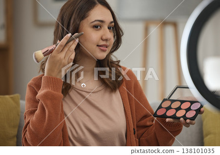 Streaming, makeup and tutorial with a woman influencer in her home to broadcast live content to viewers. Social media, product or review with a young brand ambassador in the living room for cosmetics Streaming, makeup and tutorial with a woman influencer in her home to broadcast live content to viewers. Social media, product or review with a young brand ambassador in the living room for cosmetics 138101035