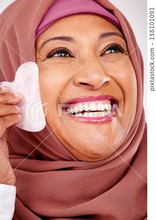 Skincare, gua sha stone and face of muslim woman closeup in studio on a white background for beauty. Spa, smile and natural with a happy mature arab person, massage with stone for antiaging treatment Skincare, gua sha stone and face of muslim woman closeup in studio on a white background for beauty. Spa, smile and natural with a happy mature arab person, massage with stone for antiaging treatment 138101091