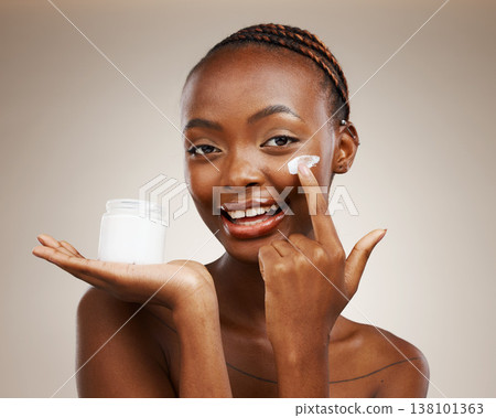 Portrait of black woman, happy or cream for wellness in studio with smile, natural cosmetics or glow. Dermatology, face or African girl model applying skincare lotion or creme on brown background 138101363