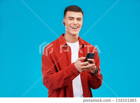 Man, phone and listening to music in studio with social media, college contact and communication on a blue background. Portrait of person or student in USA with mobile, earphones or audio streaming 138101865