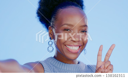 Happy, selfie and black woman with peace sign with smile isolated in a studio blue background as emoji. Happiness, cool or portrait of person with v hand gesture for social media picture online Happy, selfie and black woman with peace sign with smile isolated in a studio blue background as emoji. Happiness, cool or portrait of person with v hand gesture for social media picture online 138102311