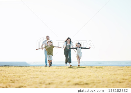 Running, parents and children on grass by ocean for bonding, relationship and relax together. Nature, travel and happy mother, father and kids on holiday, summer vacation and playing for freedom 138102882