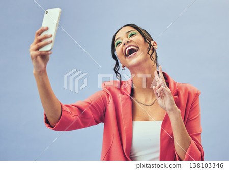 Phone, laugh selfie and woman with a peace sign from social media and picture for creative job in studio. Influencer, happy and makeup with career fashion with blue background and emoji hand sign Phone, laugh selfie and woman with a peace sign from social media and picture for creative job in studio. Influencer, happy and makeup with career fashion with blue background and emoji hand sign 138103346