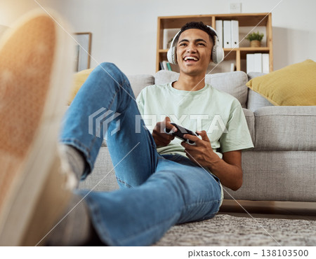Headphones, floor and man happy for video game online with controller in living room excited for virtual challenge in home. Internet, user experience and person or gamer streaming sports games Headphones, floor and man happy for video game online with controller in living room excited for virtual challenge in home. Internet, user experience and person or gamer streaming sports games 138103500