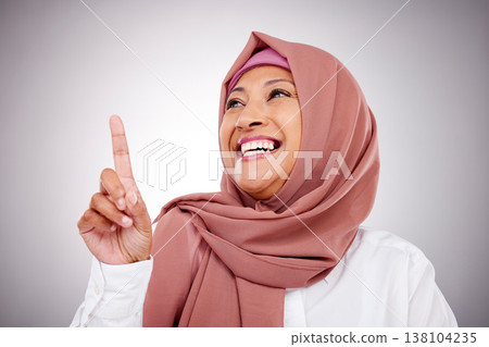 Pointing up, happy and face of Muslim woman in studio with makeup, cosmetics and beauty. Fashion, style and and Islamic person with hand gesture for news, promotion and show on gray background Pointing up, happy and face of Muslim woman in studio with makeup, cosmetics and beauty. Fashion, style and and Islamic person with hand gesture for news, promotion and show on gray background 138104235