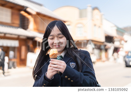 一位高中女生在川越歷史悠久的倉庫區享用軟冰淇淋。這是學校旅行或放學後的美好時光。 138105092