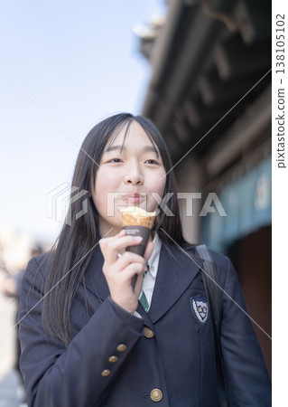 一位高中女生在川越歷史悠久的倉庫區享用軟冰淇淋。這是學校旅行或放學後的美好時光。 一位高中女生在川越歷史悠久的倉庫區享用軟冰淇淋。這是學校旅行或放學後的美好時光。 138105102