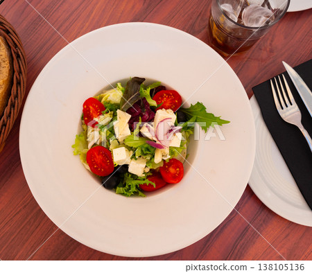 Plate of colorful salad of fresh greens, vegetables and cheese 138105136