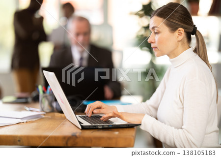 Businesswoman works in company office along with other office workers Businesswoman works in company office along with other office workers 138105183