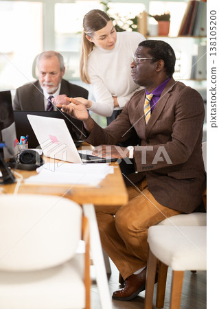 Female manager helping to man during working at laptop in office Female manager helping to man during working at laptop in office 138105200