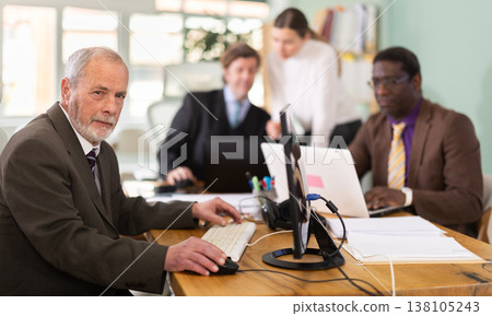 Mature man works online with a team of managers in company office. Mature man works online with a team of managers in company office. 138105243