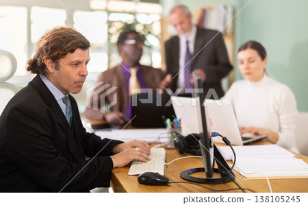 Man sitting at desk is working on laptop computer. Working day in office Man sitting at desk is working on laptop computer. Working day in office 138105245
