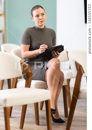 female student with a tablet in her hands listens to a lecture 138105353