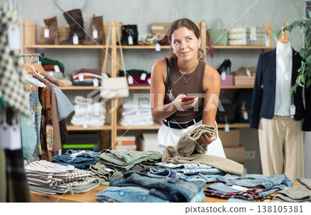 Woman scans pants on phone in store 138105381