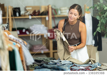 Woman standing near shelves with pants in a store Woman standing near shelves with pants in a store 138105388