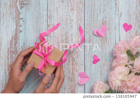 Hands holding a Mother's Day gift with pink ribbon Hands holding a Mother's Day gift with pink ribbon 138105947