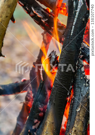 Flames dance among charred wood in a cozy campfire setting during twilight hours in an outdoor environment Flames dance among charred wood in a cozy campfire setting during twilight hours in an outdoor environment 138107740