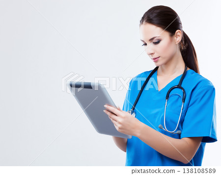 一位身穿藍色手術服的年輕女醫生,手裡拿著平板電腦。 一位身穿藍色手術服的年輕女醫生,手裡拿著平板電腦。 138108589