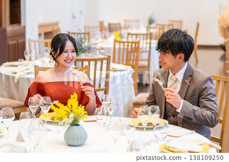 一對身著禮服和西裝的新人在婚禮場地或宴會廳用餐。 138109250