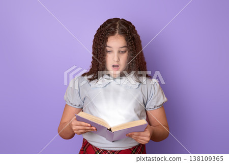 Curious Girl Reading a Book with Fascination Against a Soft Purple Background Curious Girl Reading a Book with Fascination Against a Soft Purple Background 138109365
