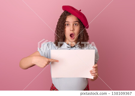 Surprised Child in a Red Beret Pointing at a Blank White Sign Against a Pink Background 138109367