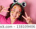 Cheerful Girl with Colorful Candy Decorations Smiling Playfully Against a Pink Background 138109406