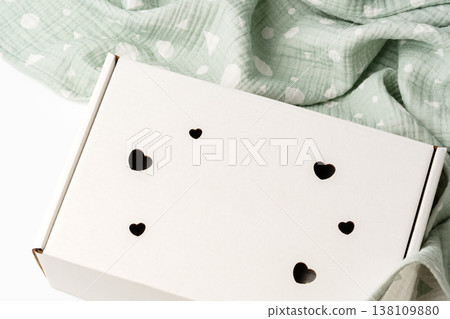 Gift box with heart cutouts on a soft, patterned blanket in a bright room 138109880